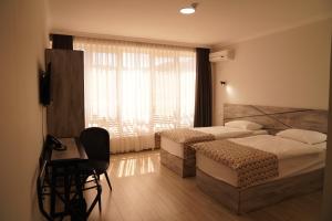 a bedroom with two beds and a desk and a window at Aventus Hotel in Akhaltsikhe +52 photos