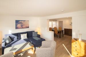 a living room with a blue couch and a dining room at Haus Roseneck App.1 in Hörnum