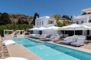 a swimming pool with chairs and umbrellas next to a house at Chrysalis Nature Villa 9 in Kampos Paros