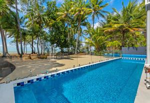 a swimming pool with palm trees and a beach at Tenterfield Beachfront Luxury 4 Bedroom Holiday Home in Oak Beach