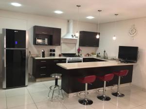 a kitchen with black appliances and red bar stools at Napoles Condo Suites in Mexico City