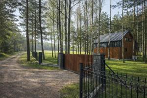 a fence in front of a building in a field at Cieniówka, dom w lesie, Kije in Kije
