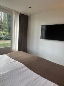 a bedroom with a bed with a flat screen tv on the wall at Huize Hölterhof Wellness Hotel Restaurant in Enschede