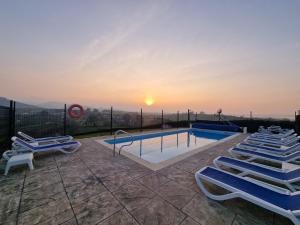 a swimming pool with lounge chairs and the sunset at Hotel Verdemar by Grupo A Cobijo in Lamadrid