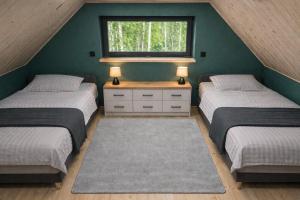 a attic bedroom with three beds and a window at Cieniówka, dom w lesie, Kije in Kije