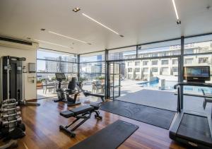a gym with cardio equipment and a large window at Sky Tower Serenity + Rooftop Pool in Auckland