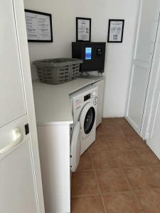 a laundry room with a washing machine and a tv at APPARTEMENT sognu di rena G1 in San-Nicolao