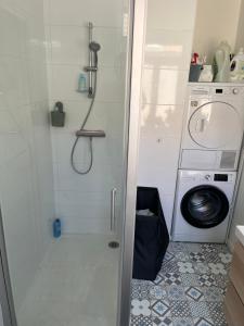 a bathroom with a shower and a washing machine at Petite chambre in La Madeleine