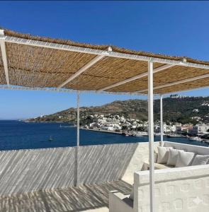 a view of the ocean from a patio with a straw umbrella at Villa Iza in Skala