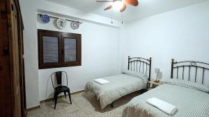 a bedroom with two beds and a chair and a window at casa rural Ribera del Hueznar in Constantina +37 photos