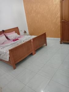 a wooden bed in a room with a tiled floor at Maison au rez-de-chaussée à Mahdia rejiche in Mahdia