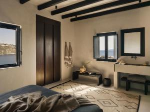 a bedroom with a bed and a sink and windows at ananea Mykonos - Adults Only in Ornos +101 photos