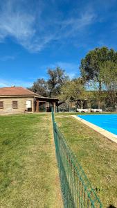 a fence in front of a house and a swimming pool at casa rural Ribera del Hueznar in Constantina