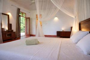 a bedroom with a large white bed with a canopy at Bluewind Hotel in Tangalle +21 photos