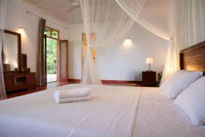 a bedroom with a large white bed and a window at Bluewind Hotel in Tangalle