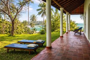 a porch with two benches and the ocean in the background at Bluewind Hotel in Tangalle