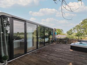 a house with glass walls and a deck with a hot tub at Countryside Pod Retreat in Durston