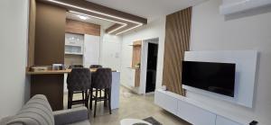 a living room with a television and a bar with stools at Apartman Kristal, Vrnjačka Banja in Vrnjci
