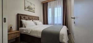 a bedroom with a large bed with a window at Apartman Kristal, Vrnjačka Banja in Vrnjci