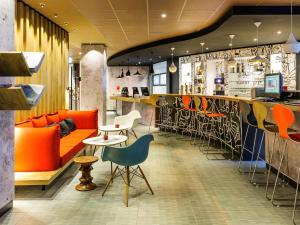 a restaurant with a bar with orange chairs and a counter at Ibis Hamburg City in Hamburg