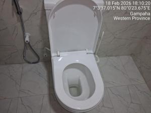 a white toilet in a bathroom with a hose at Slayan-1 properties in Mudungoda +3 photos