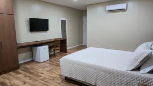 a bedroom with a bed and a desk with a television at Pousada Trapiche in Pelotas +13 photos