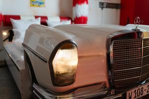 an old car is parked next to a bed at Motorworld Inn Hotel Böblingen in Böblingen