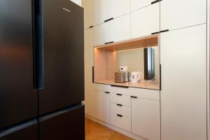 a kitchen with white cabinets and a black refrigerator at Rossio individual Suites Lisbon in Lisbon