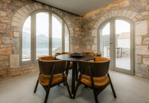 a dining room with a table and chairs and windows at Nest Limeni in Limeni