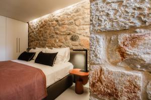 a bedroom with a bed and a stone wall at Nest Limeni in Limeni +136 photos