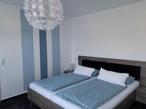 a bedroom with two beds and a chandelier at Op-England-I-mit-Terrasse-grossem-Garten in Nordstrand