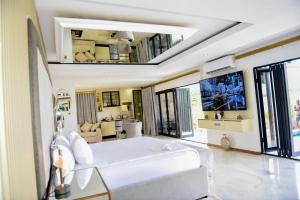 a bedroom with a large white bed and a living room at Nandoni Waterfront Resort in Thohoyandou