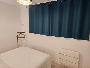 a bedroom with a bed and a blue curtain at Appartement paisible in Quévert