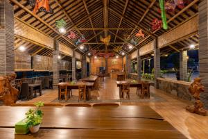 a restaurant with wooden tables and chairs and a ceiling at Glamping Camphills in Gunungpicung