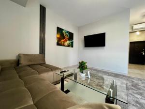 a living room with a couch and a glass table at Calyra Aparthotel 12 SELF CHECK-IN #Otopeni #Airport #Therme #Bucharest in Otopeni