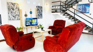 a living room with two red chairs and a tv at Infinity Villa in Anuradhapura