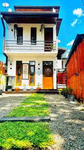 a white house with orange doors and a yard at Infinity Villa in Anuradhapura