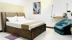 a bedroom with a bed and a blue chair at Infinity Villa in Anuradhapura
