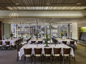 a banquet hall with white tables and chairs at Novotel Queenstown Lakeside in Queenstown