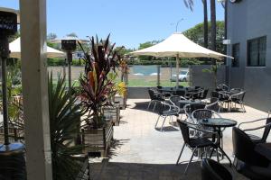 an empty patio with tables and chairs and umbrellas at Rocky Glen Hotel Motel Gladstone in Gladstone