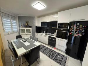 a kitchen with a table and a black refrigerator at Neretva Paradise Mostar in Mostar