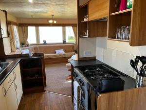a kitchen with a stove and a living room at California cliffs caravan in Great Yarmouth