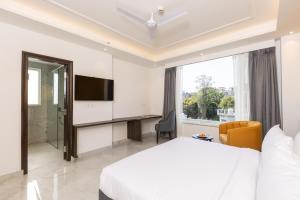 a bedroom with a bed and a desk and a television at Hotel HiStays, Dehradun in Dehradun