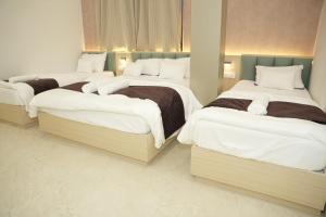 a bedroom with three beds with white sheets at Samyak Stay in Ujjain
