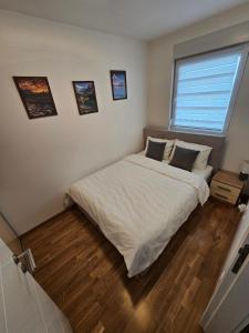 a bedroom with a bed with white sheets and a window at Apartman Petrovic-5 min by walk to Center,Doboj City Park in Doboj