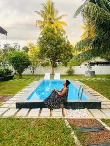 a woman sitting next to a swimming pool at Villa Tropical Oasis in Balapitiya