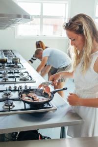 a woman cooking food in a pan on a stove at Finlay Jack's Backpackers in Taupo