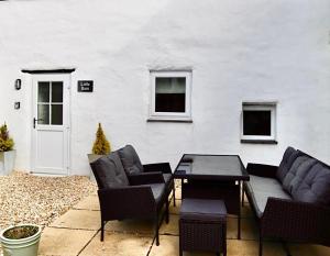 a patio with a table and chairs and a white wall at Little Barn, Greendale Farm in Barnstaple +30 photos
