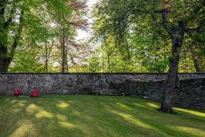 a stone wall with two red chairs and a tree at Apartmány U Parku in Vrchlabí