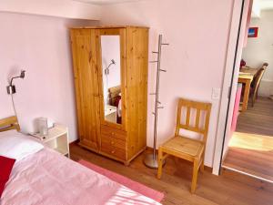a bedroom with a wooden cabinet and a chair at Pilgerwohnung in Wald